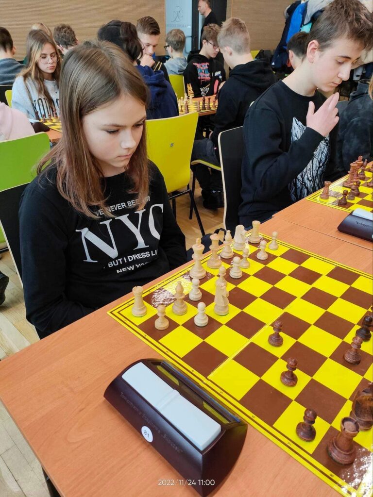 Osoby w pokoju siedzące i grające w szachy