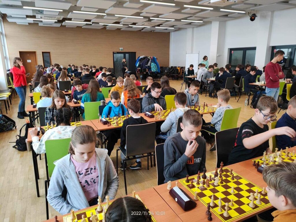 Osoby w pokoju siedzące i grające w szachy