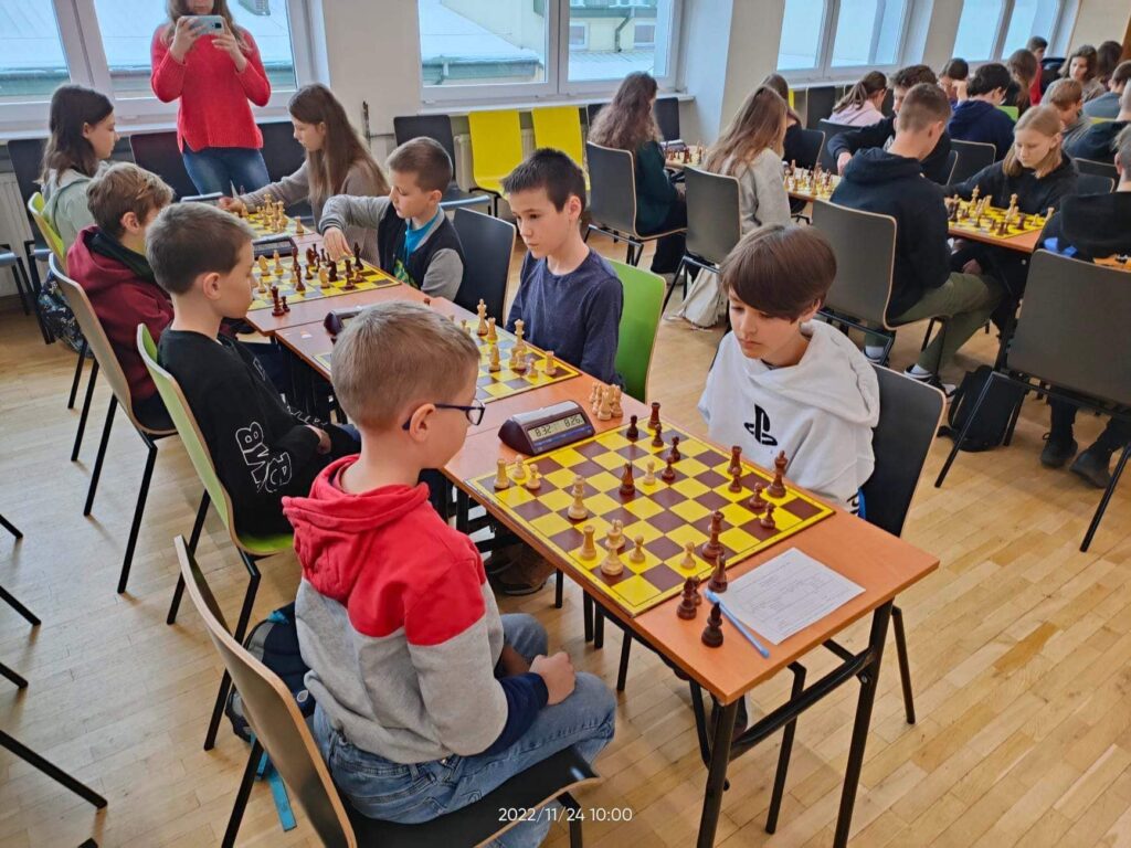 Osoby w pokoju siedzące i grające w szachy