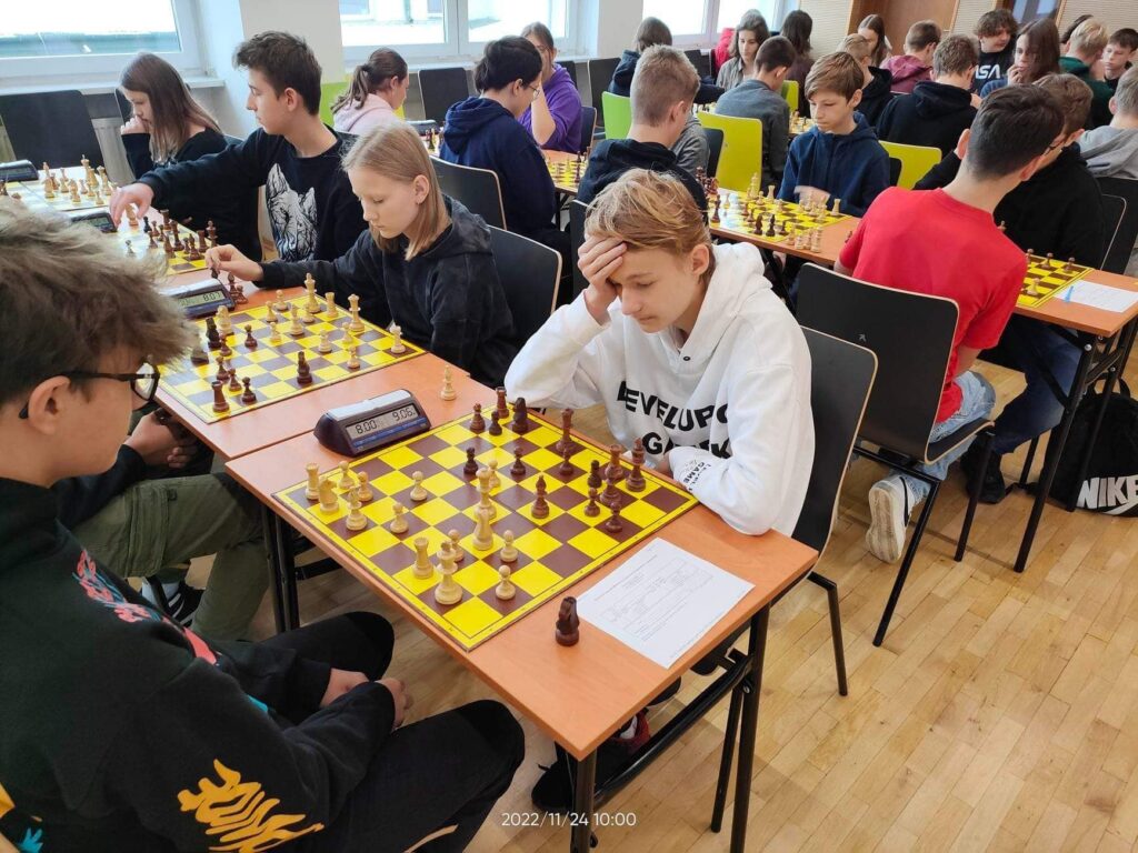 Osoby w pokoju siedzące i grające w szachy