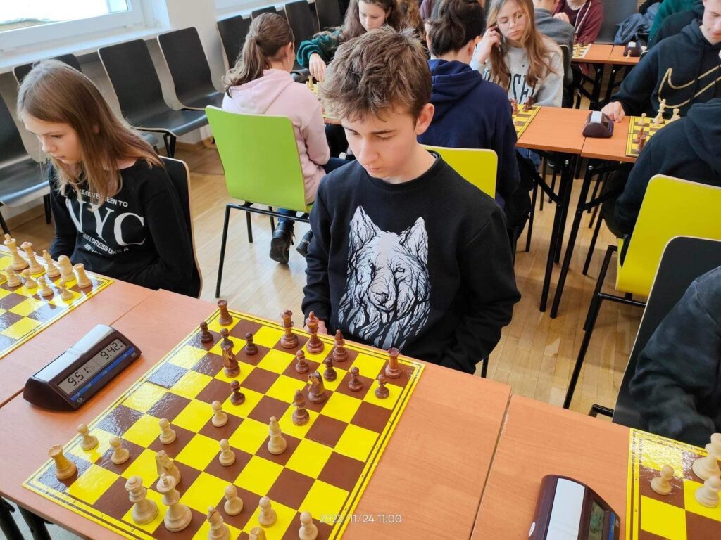 Osoby w pokoju siedzące i grające w szachy