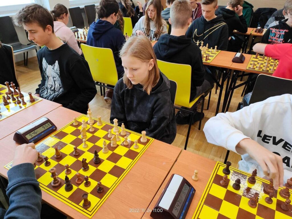 Osoby w pokoju siedzące i grające w szachy